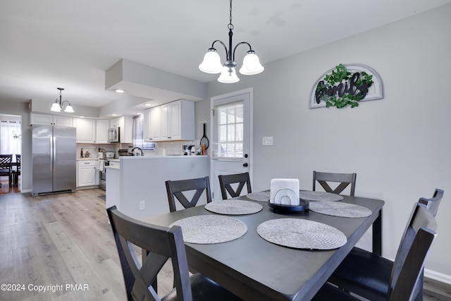 dining room with light wood-style flooring, a chandelier, and baseboards