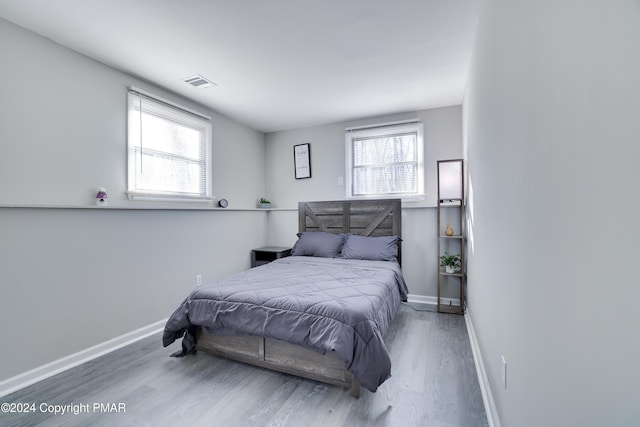 bedroom with baseboards, visible vents, and wood finished floors