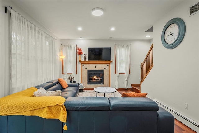 392 Hemlock Dr, Tobyhanna, PA 18466 - living area featuring a baseboard radiator, wood finished floors, a tiled fireplace, recessed lighting, and stairs