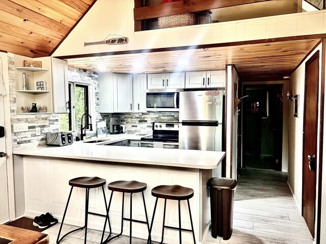 256 Partridge Dr, Pocono Lake, PA 18347 - kitchen with appliances with stainless steel finishes, open shelves, a peninsula, a sink, and backsplash