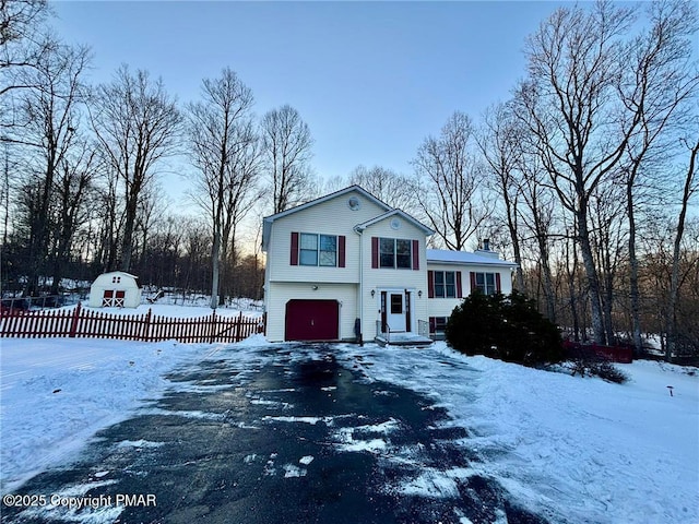 view of front of home with driveway, an attached garage, and fence