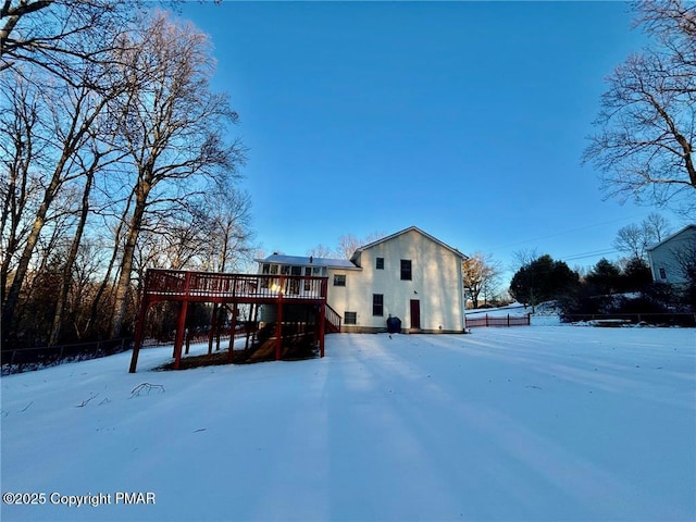 snow covered rear of property featuring stairway and a deck