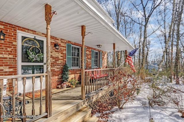 snow covered deck featuring a porch