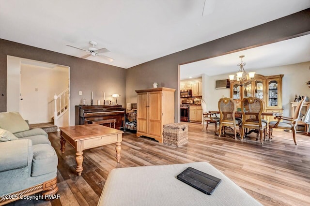 living room with ceiling fan with notable chandelier and light wood-type flooring