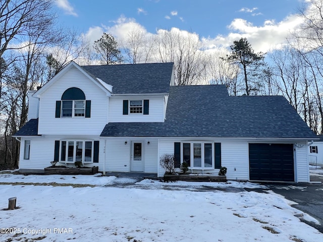 traditional home featuring roof with shingles and an attached garage