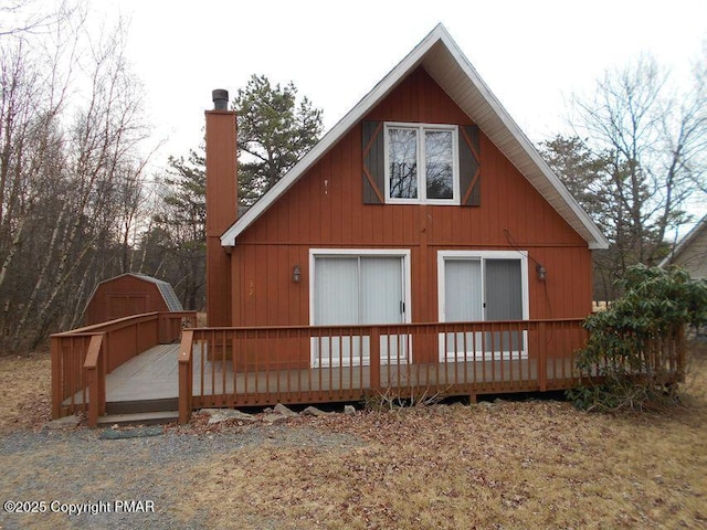 rear view of house with a deck, an outdoor structure, and a chimney