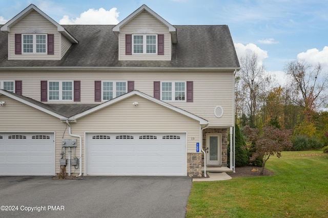 view of property with a garage, driveway, stone siding, roof with shingles, and a front yard