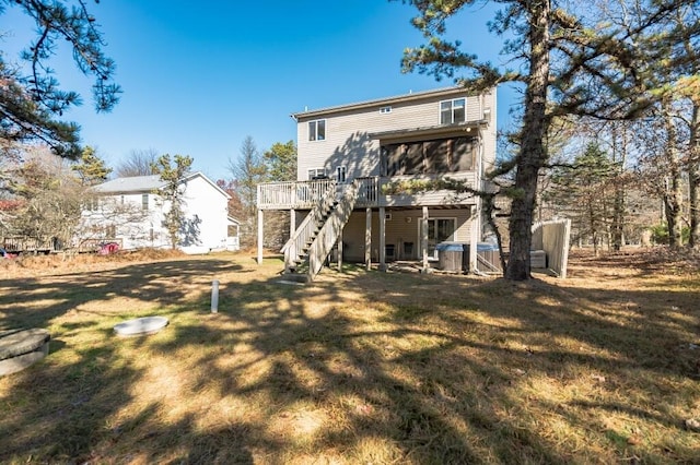 rear view of house with a deck, a lawn, and stairs