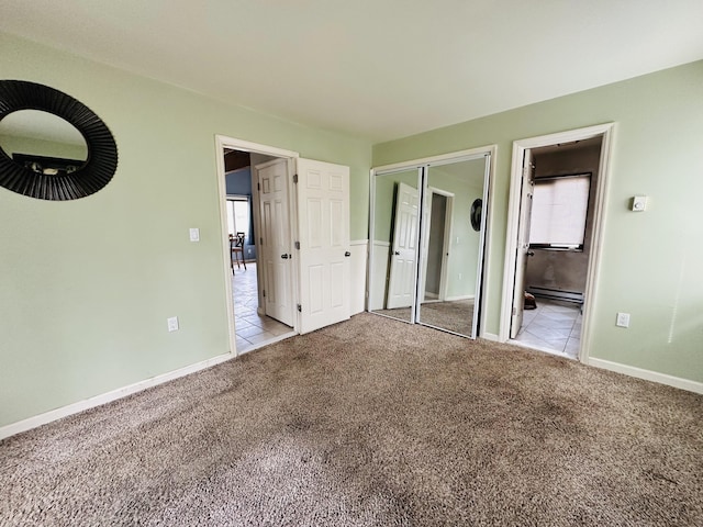 unfurnished bedroom featuring carpet floors, ensuite bathroom, baseboards, and tile patterned floors
