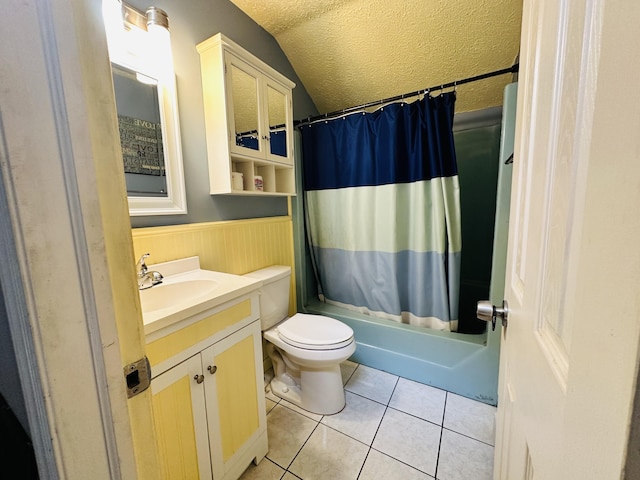 bathroom with a textured ceiling, wainscoting, vanity, tile patterned floors, and lofted ceiling