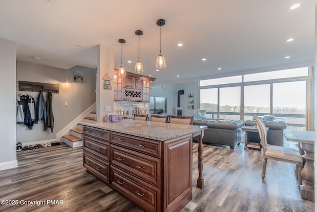 kitchen featuring a breakfast bar, light stone counters, dark wood finished floors, freestanding refrigerator, and recessed lighting