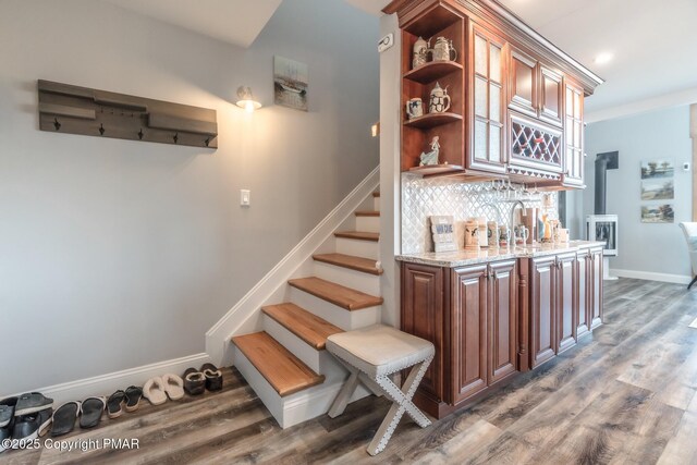 bar featuring dark hardwood / wood-style flooring, decorative backsplash, and light stone countertops