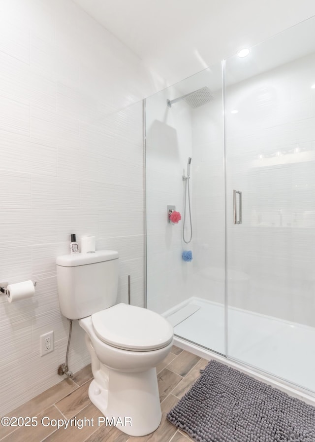 bathroom featuring an enclosed shower, toilet, tile walls, and wood finish floors