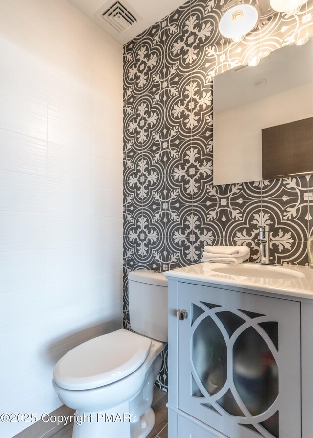 bathroom featuring vanity, toilet, and visible vents