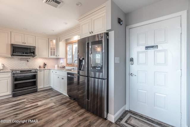 kitchen with visible vents, a sink, tasteful backsplash, stainless steel appliances, and light stone countertops