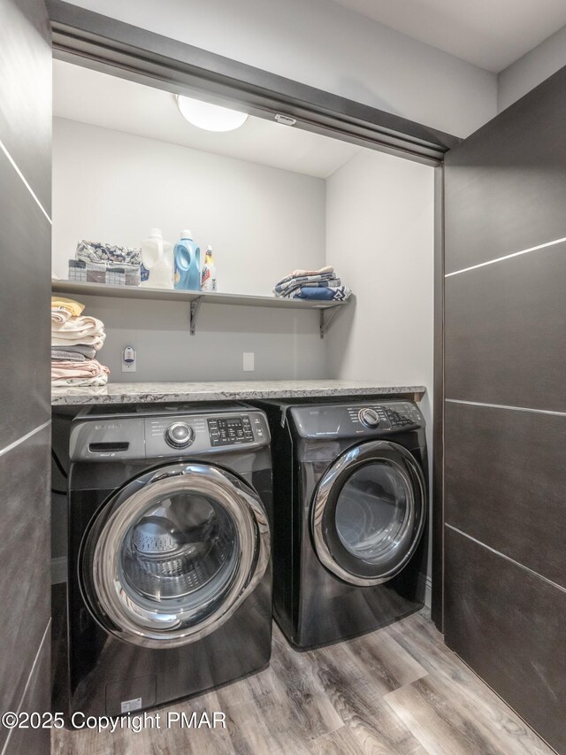 clothes washing area featuring wood-type flooring and washing machine and dryer