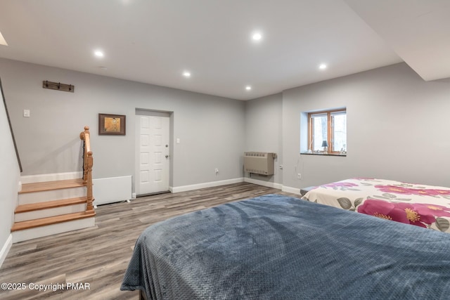 bedroom with heating unit, recessed lighting, baseboards, and wood finished floors