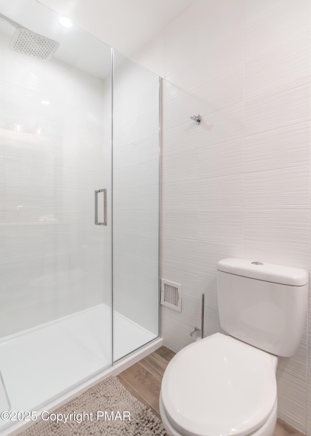 full bath featuring visible vents, a shower stall, tile walls, and toilet