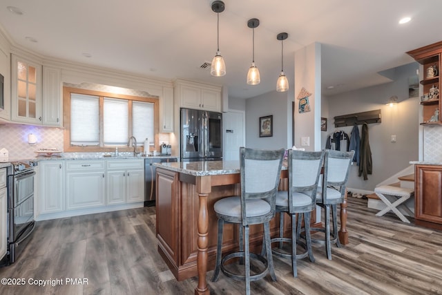 kitchen featuring decorative backsplash, light stone counters, dark wood-style floors, and stainless steel appliances