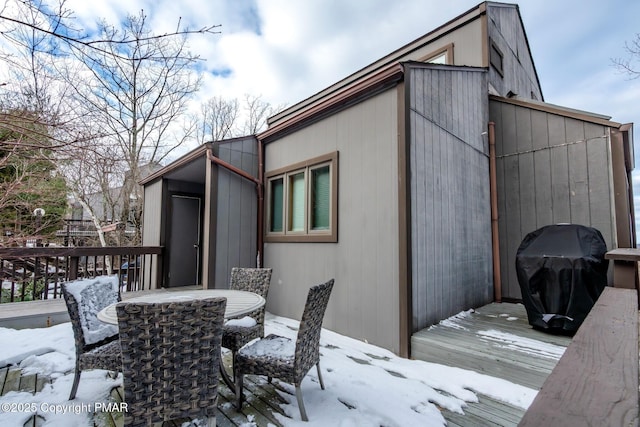 snow covered patio featuring outdoor dining area, area for grilling, and a deck