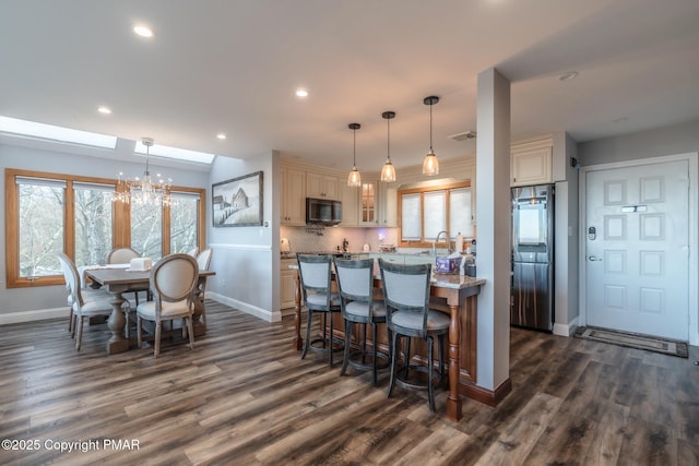 kitchen with smart refrigerator, tasteful backsplash, an inviting chandelier, a breakfast bar area, and glass insert cabinets