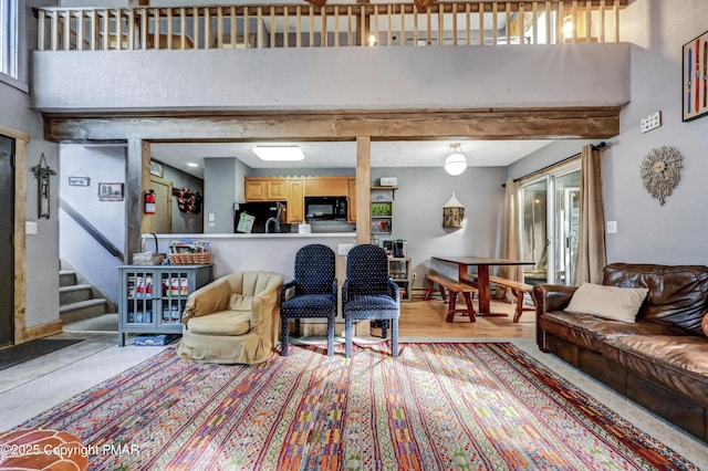 living room featuring light wood-style flooring, plenty of natural light, stairway, and a towering ceiling