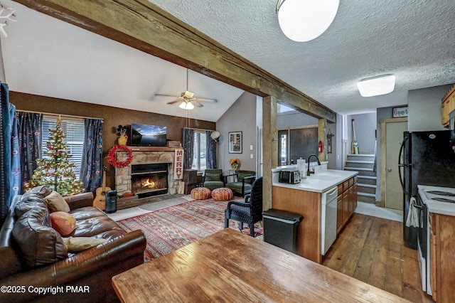 kitchen with vaulted ceiling with beams, a fireplace, open floor plan, a sink, and dishwasher