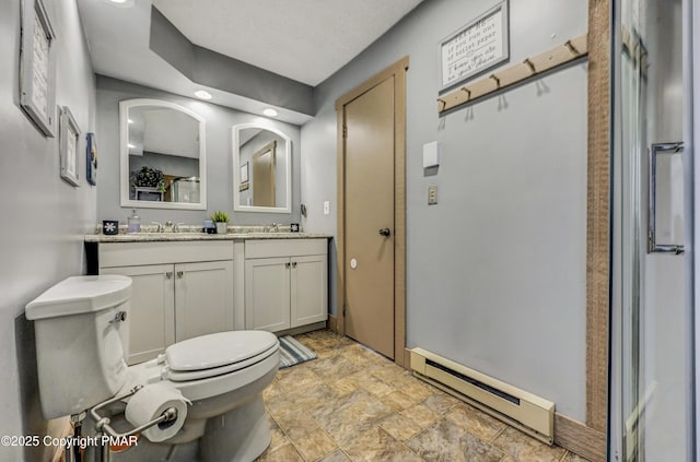 bathroom with a baseboard heating unit, a sink, toilet, and double vanity