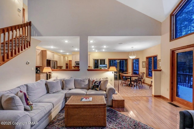 living room featuring recessed lighting, visible vents, light wood-style floors, stairs, and vaulted ceiling