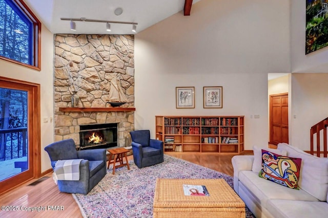 living room featuring a towering ceiling, a fireplace, wood finished floors, and visible vents