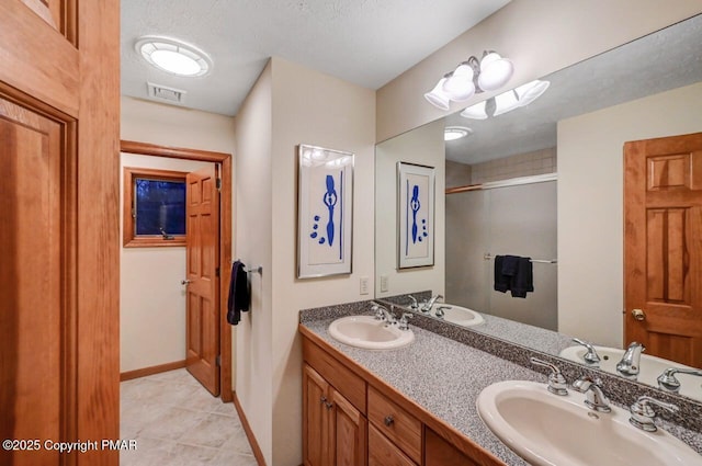 full bathroom with visible vents, a sink, a shower stall, and a textured ceiling