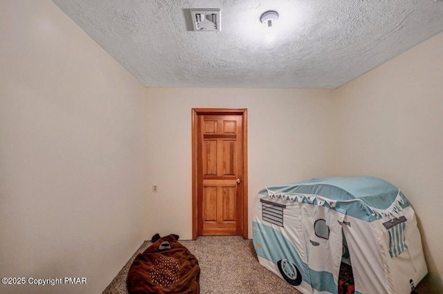 bedroom with a textured ceiling, carpet flooring, and visible vents