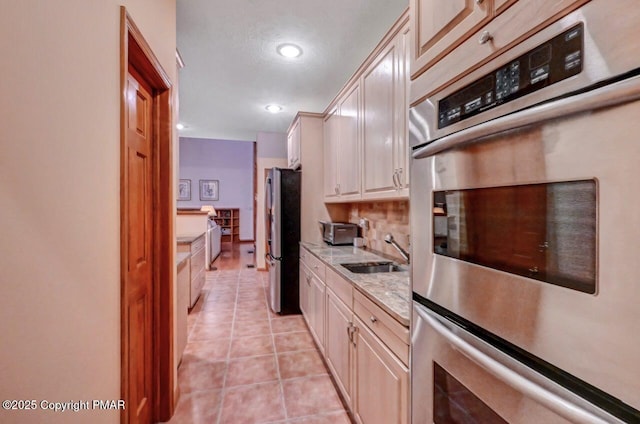 kitchen featuring light tile patterned flooring, recessed lighting, stainless steel appliances, a sink, and decorative backsplash