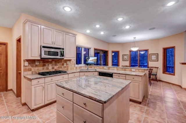 kitchen with black gas cooktop, a peninsula, a center island, tasteful backsplash, and stainless steel microwave