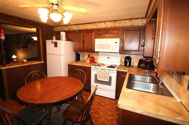 kitchen with white appliances, light countertops, a sink, and brown cabinetry