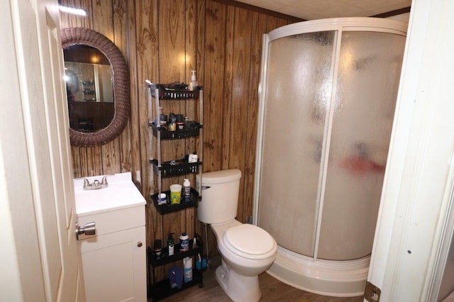 full bathroom with wooden walls, a shower stall, toilet, and vanity