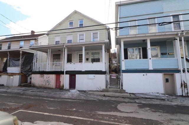 view of front facade with covered porch, a balcony, and a gate