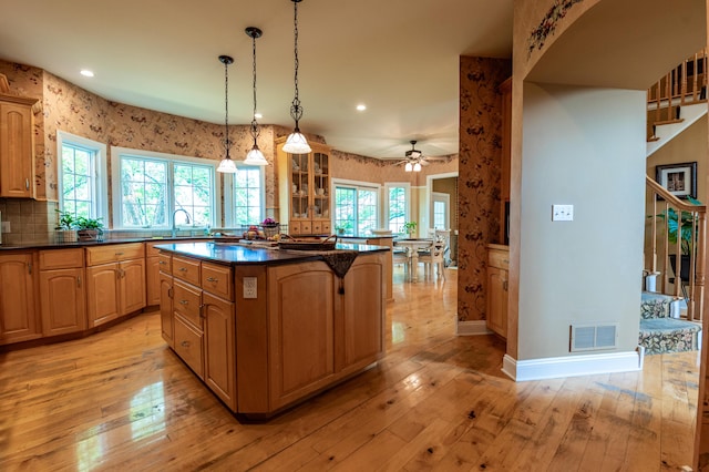 49 Central Dr, Easton, PA 18045 - kitchen with dark countertops, a center island, glass insert cabinets, a ceiling fan, and light wood finished floors