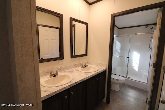 bathroom with double vanity, a stall shower, a sink, and toilet