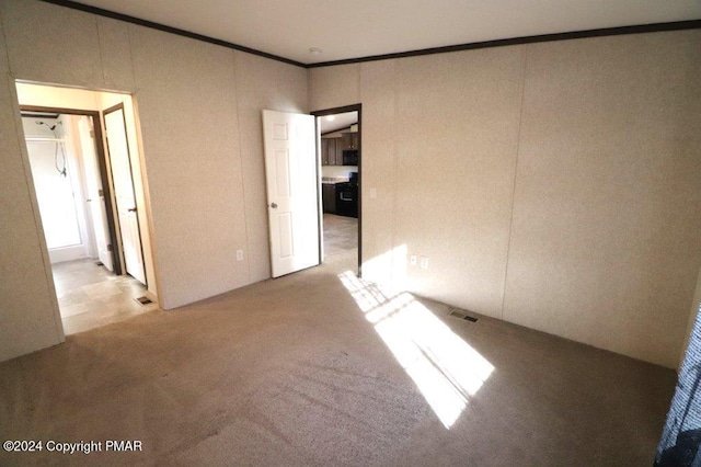 spare room featuring carpet floors, ornamental molding, and visible vents