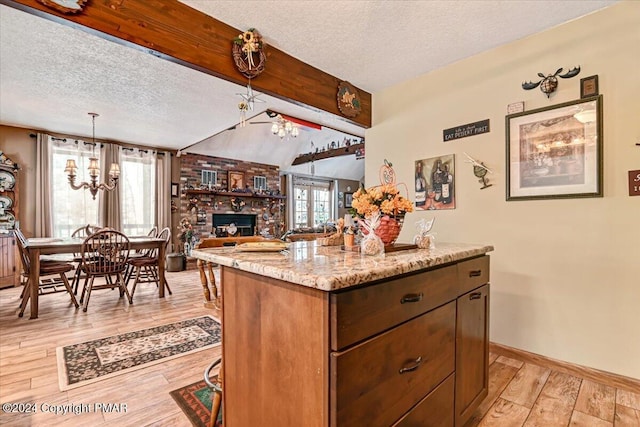 kitchen with a wealth of natural light, a notable chandelier, light wood-style flooring, and a textured ceiling