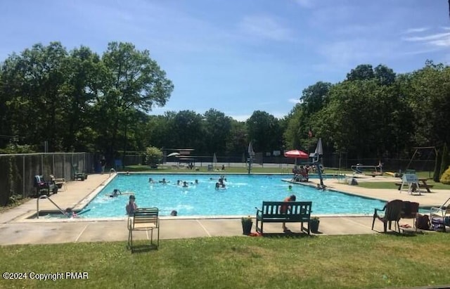 community pool with a patio area, fence, and a yard