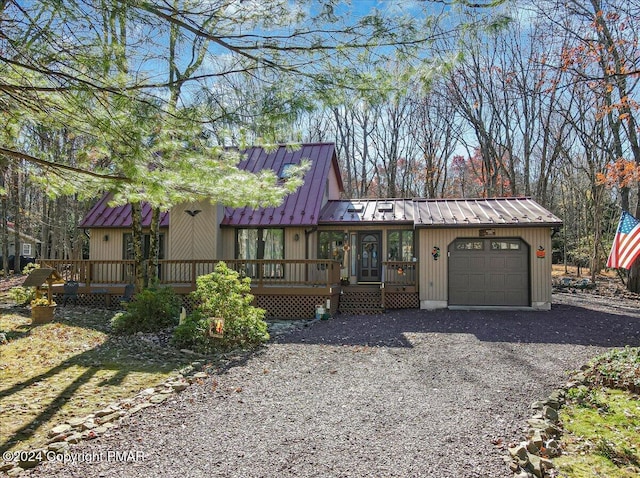 view of front of property with a garage, driveway, metal roof, and a standing seam roof