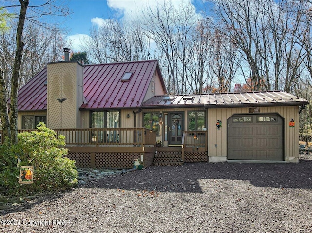 view of front of home with gravel driveway, a chimney, an attached garage, a standing seam roof, and metal roof