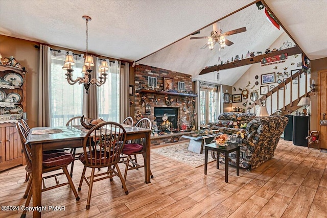 dining space with a textured ceiling, vaulted ceiling, stairs, a brick fireplace, and light wood finished floors