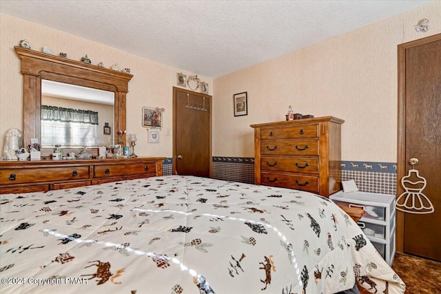 bedroom featuring a textured ceiling and wallpapered walls