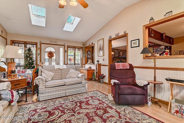 living area with ceiling fan, wainscoting, vaulted ceiling, and wood finished floors