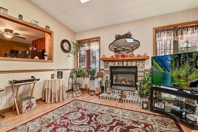 sitting room featuring ceiling fan, a fireplace, wood finished floors, baseboards, and wallpapered walls