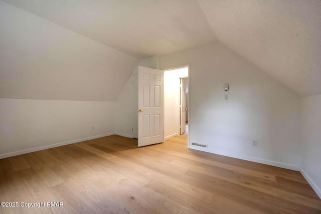 bonus room with vaulted ceiling and light hardwood / wood-style floors