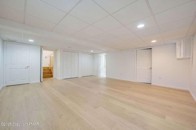 basement with a drop ceiling and light hardwood / wood-style floors